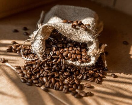 A burlap sack spills aromatic roasted coffee beans in warm natural light.